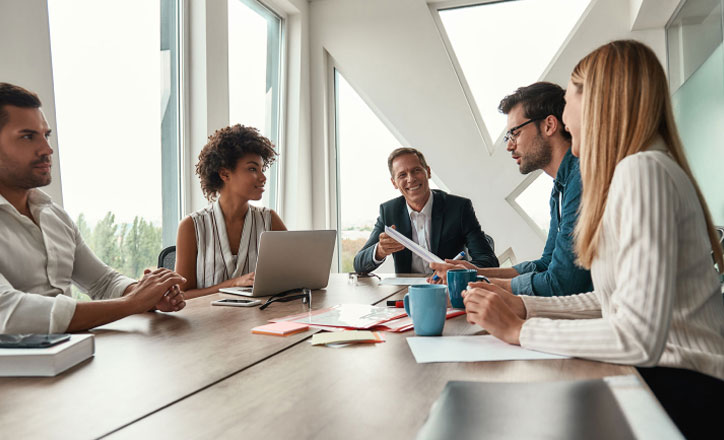 A man sitting at the head of a table during a meeting.