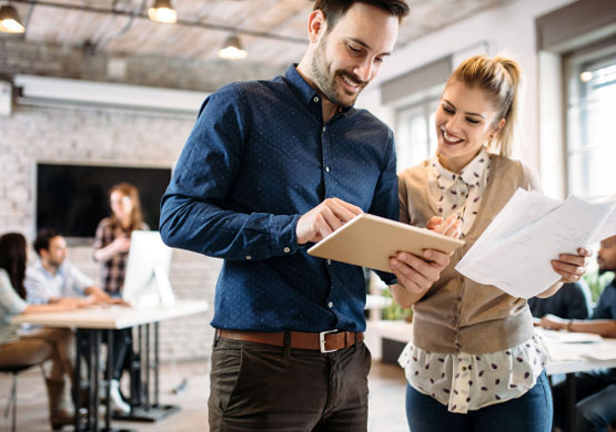 Two employees looking at a tablet and smiling.